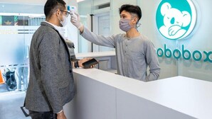 Un área de recepción con diseño moderno, un separador de vidrio y un logotipo en la pared.