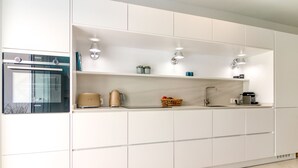 A modern kitchen with white cabinetry, a built-in oven, and under-cabinet lighting. - Azahara Marbella - Modern decorated apartment with lovely terrace view (Marbella)