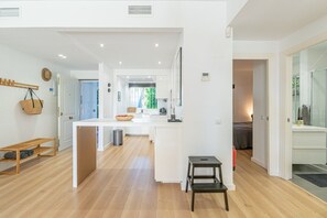 Un intérieur moderne avec un espace cuisine central, une table à manger et un petit coin salon doté d’un banc.
