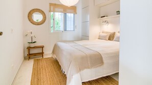 A bedroom with a bed, bedside table, lamp, and a window with a view of greenery. - Azahara Marbella - Modern decorated apartment with lovely terrace view (Marbella)