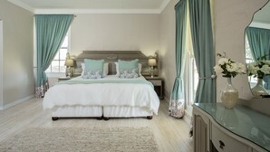 Quarto com uma cama grande, duas mesas de cabeceira, uma cômoda e um espelho.