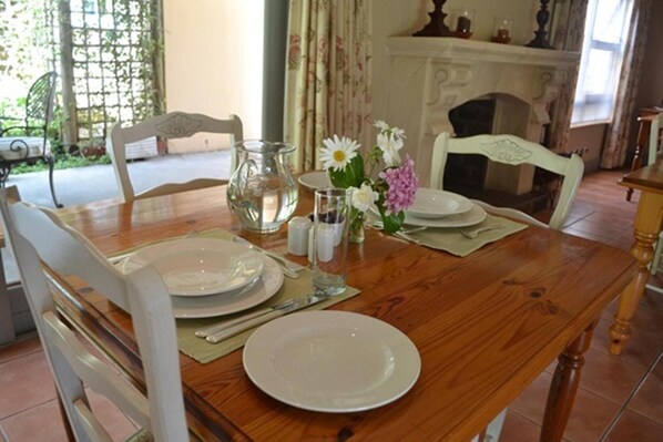 A dining table set with white plates, a pitcher, and a vase with flowers.