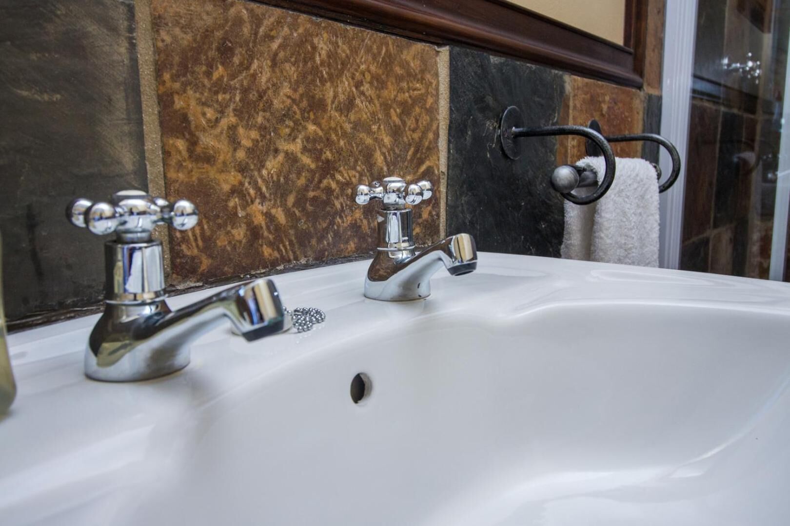 Un lavabo de bany amb dues aixetes cromades i una barra de tovalloles amb una tovallola.