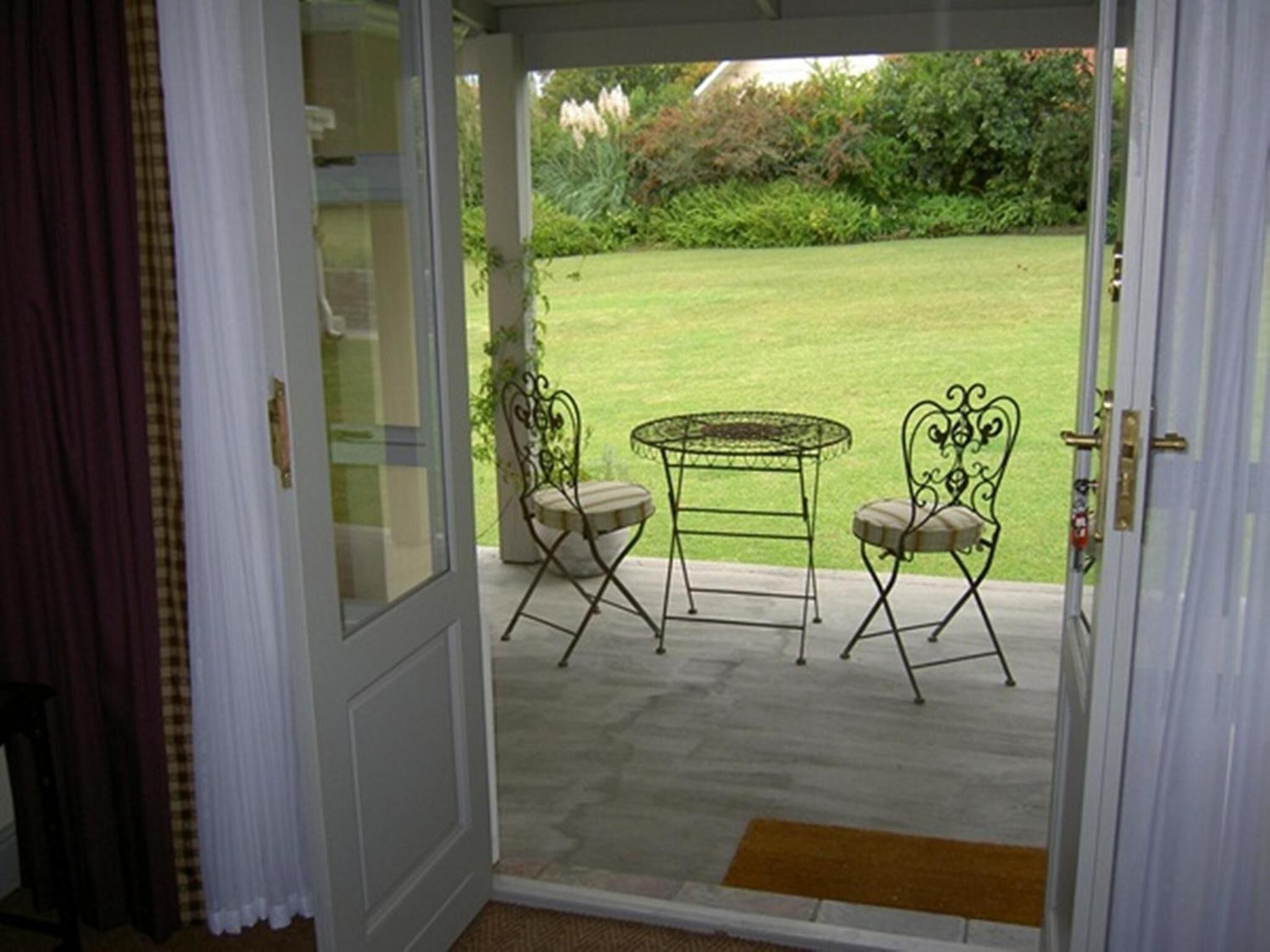 A glass door leading to an outdoor patio with a table and two chairs.
