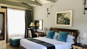Habitación de hotel con una cama grande, un escritorio con lámpara, una silla, un armario y un cuadro en la pared.