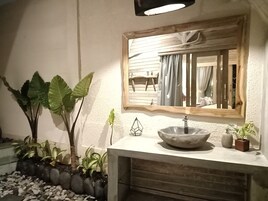 A bathroom with a large mirror, a sink, and various plants.