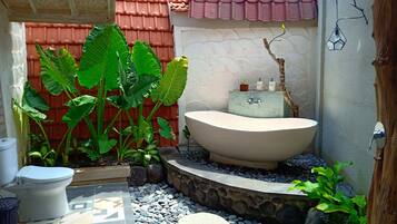 A small, private bathroom with a freestanding bathtub, a toilet, and a sink.