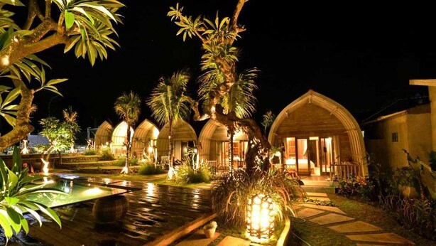 A nighttime view of a resort with overwater bungalows, a swimming pool, and well-lit pathways. - Kompyang Cottage (Penida Island)