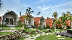 A resort with multiple bungalow-style buildings, a well-maintained garden with pathways, and palm trees. - Kompyang Cottage (Penida Island)