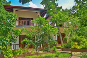 A two-story building with a balcony, surrounded by lush greenery and a well-maintained garden. - Heaven in Satin Woods Rekawa (Rekawa)