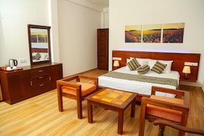 Une chambre d’hôtel avec un lit en bois, deux tables de chevet, un miroir, un bureau et une chaise.