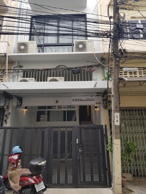 Secure gated entrance with air conditioning units and a balcony.