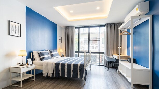 A modern hotel room with a bed, desk, and wardrobe. - Cozy Studio 1 in Sathorn - BTS Saint Louis (Bangkok)