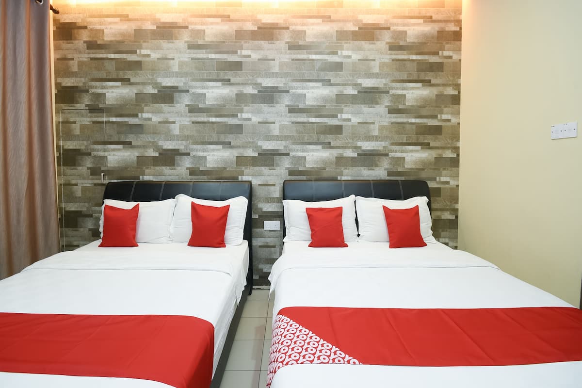 Quarto de hotel com duas camas, cada uma com roupa de cama branca e detalhes vermelhos, em frente a uma parede com textura.