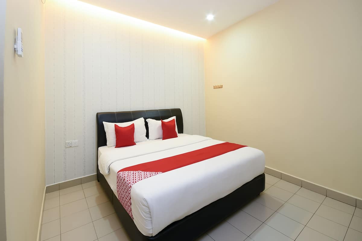 Cama bem arrumada com cabeceira preta, roupa de cama branca e vermelha, e um cobertor com padrão vermelho e branco.