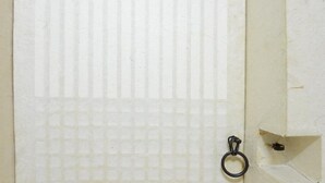 En dörr med ett mönstrat, strukturerat utseende och ett metallhandtag i form av en ring.