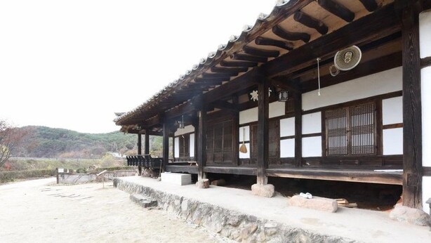En traditionell japansk byggnad med en träkonstruktion, stentrappor och utsikt över det omgivande landskapet.