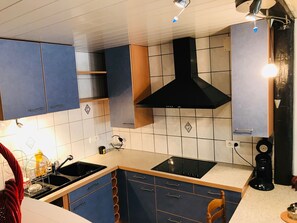 Eine Küche mit blauen Schränken, einer schwarzen Dunstabzugshaube, einem Spülbecken und einer Kaffeemaschine.