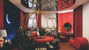 Une chambre à coucher luxueuse avec un lit à baldaquin, un bureau et un canapé rouge.
