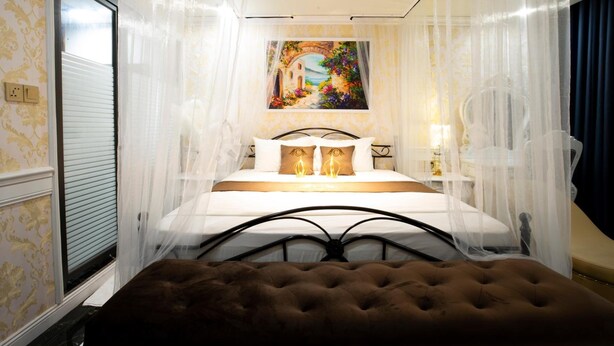 Une chambre à coucher avec un lit, un tableau décoratif et une table de chevet avec une lampe.
