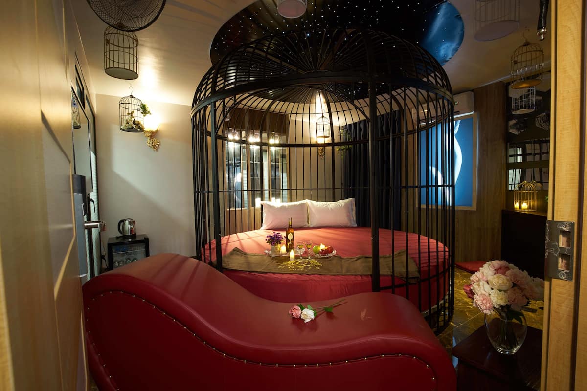 A room with a circular bed, a red sofa, a vase with flowers, and a wall-mounted light fixture.
