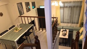A dining area with a table and chairs, a staircase, and a living area with a sofa and a small table. - Yi Jia Homestay (Jinning)