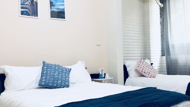 A hotel room with two beds, a window with curtains, a wall-mounted air conditioner, and two framed pictures. - Yi Jia Homestay (Jinning)