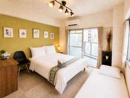 Una habitación de hotel con cama, escritorio, silla, ventana con cortinas y decoración en la pared.