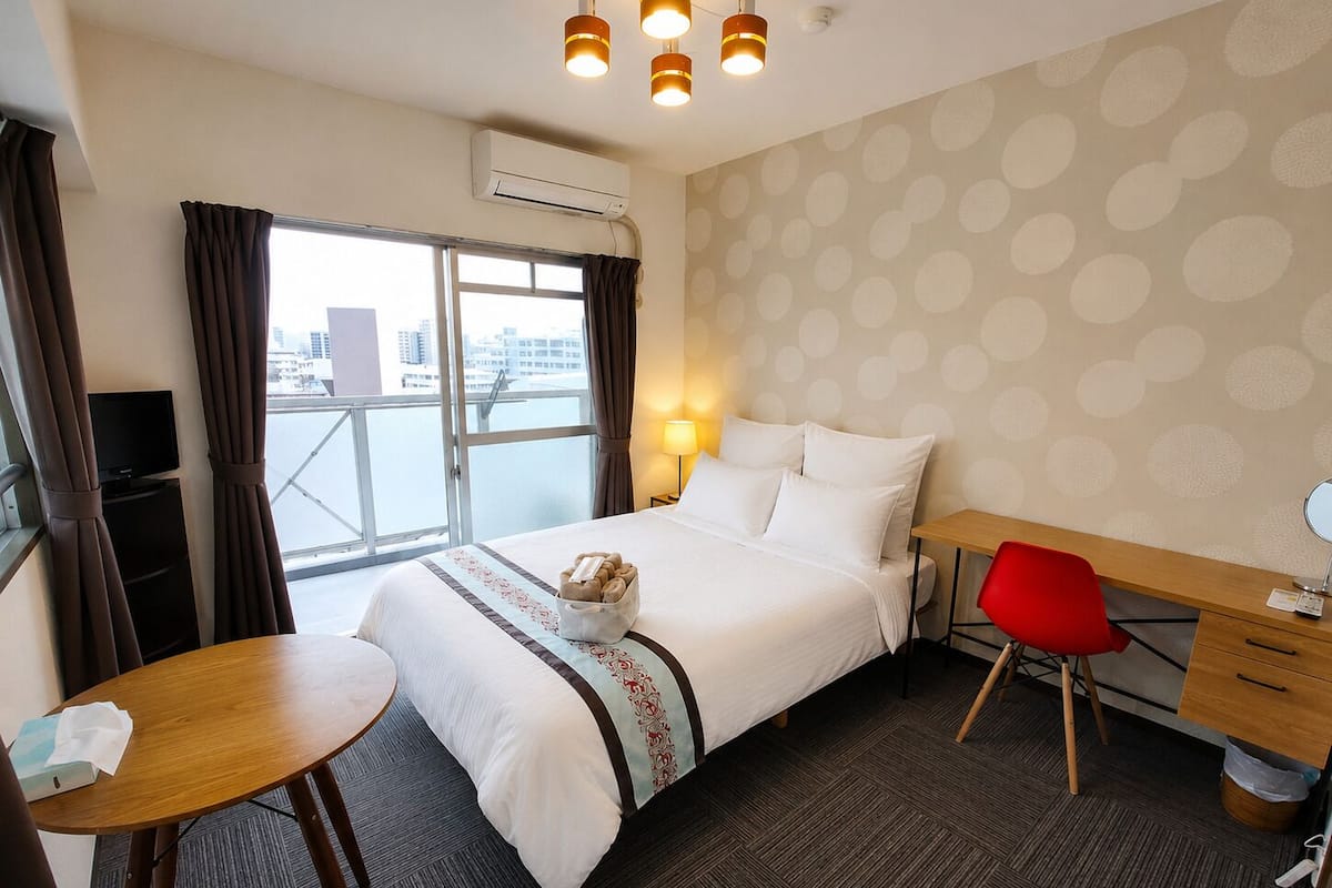 Una habitación de hotel con cama, escritorio, silla y vistas a la ciudad.