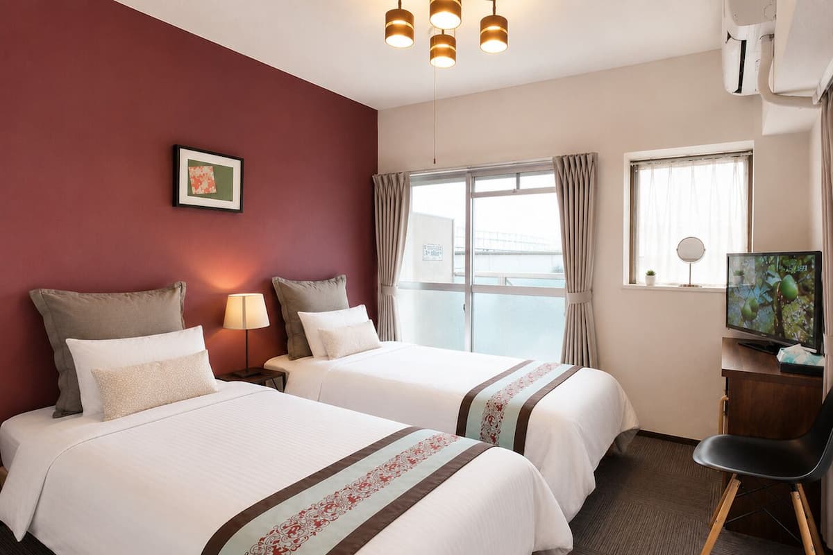Habitación de hotel con dos camas, televisión, escritorio y ventana con cortinas.