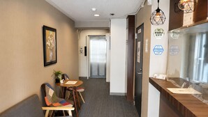 A reception area with a sofa, chairs, a small table, and a counter. - COCO Fukuoka Chiyo (Fukuoka)