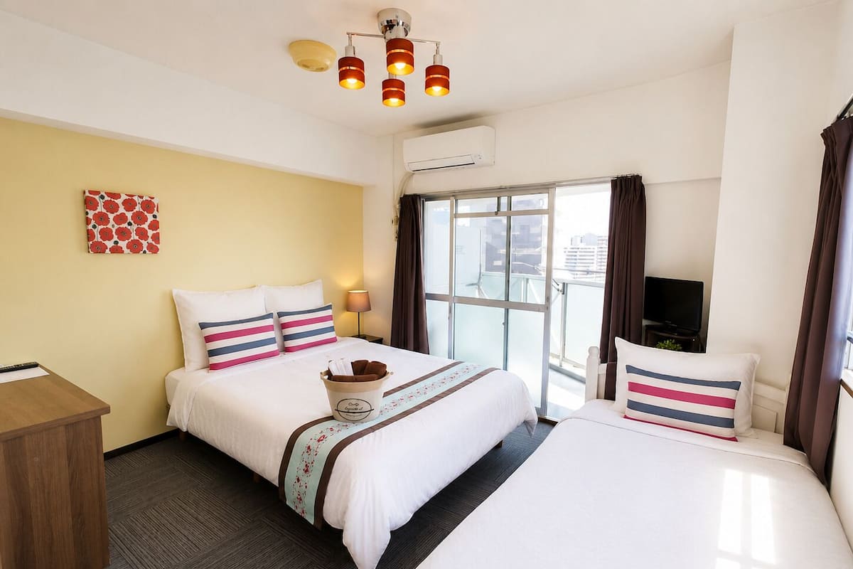 Habitación de hotel con dos camas, televisión, escritorio y ventana con vista.