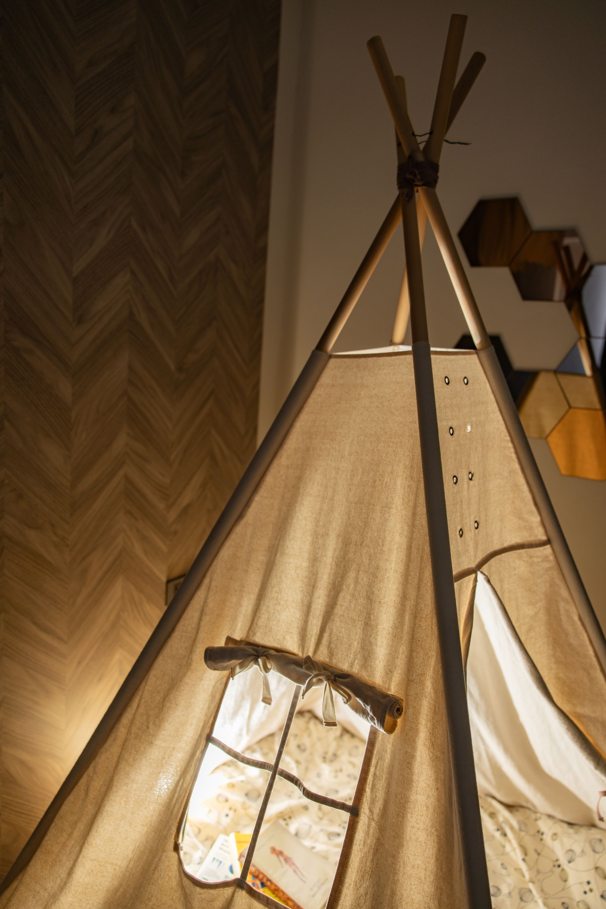 A tent-like structure with a window and a door, set against a wooden herringbone floor.
