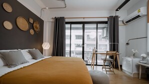 Ett modernt sovrum med en stor säng, ett skrivbord och utsikt över staden.