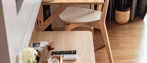 A wooden dining table with chairs, a remote control, and a small plant on a wooden floor.