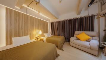A hotel room with two beds, a sofa, a lamp, and curtains.