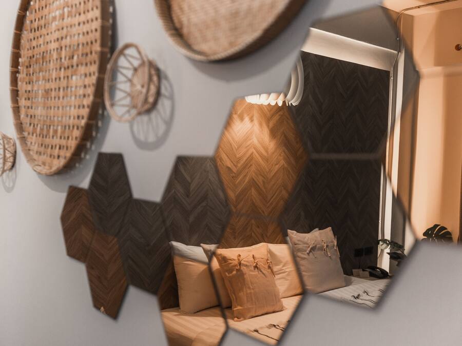 Un intérieur moderne avec un mur orné d’un motif géométrique, un canapé avec des coussins et des objets décoratifs, comme des paniers tressés et une horloge murale.