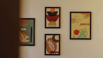 A dining area with a wooden table and chairs, and four framed artworks on the wall.