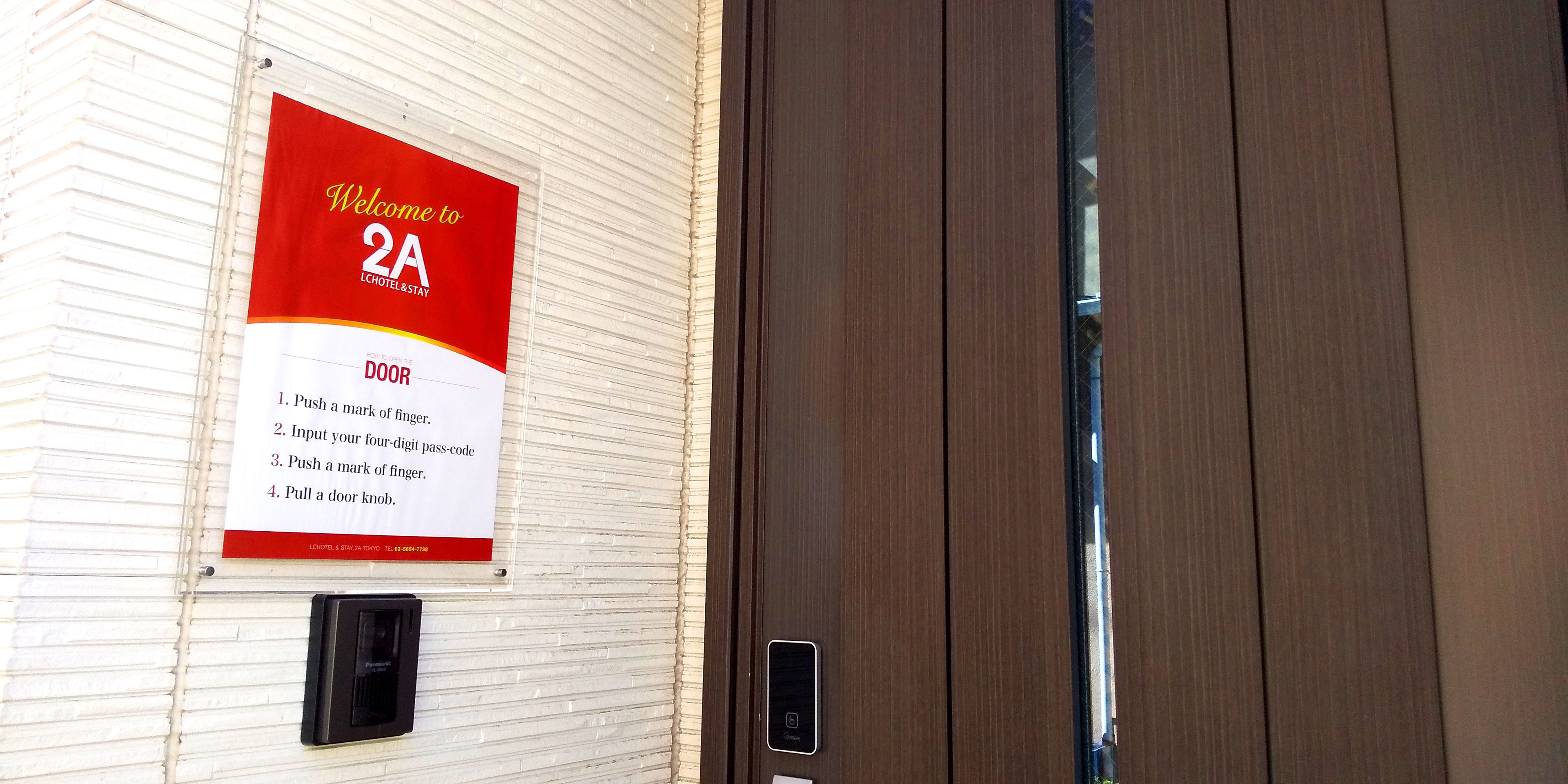 A door with a sign instructing to push a mark of finger, input a four-digit pass-code, push a mark of finger again, and pull a door knob.