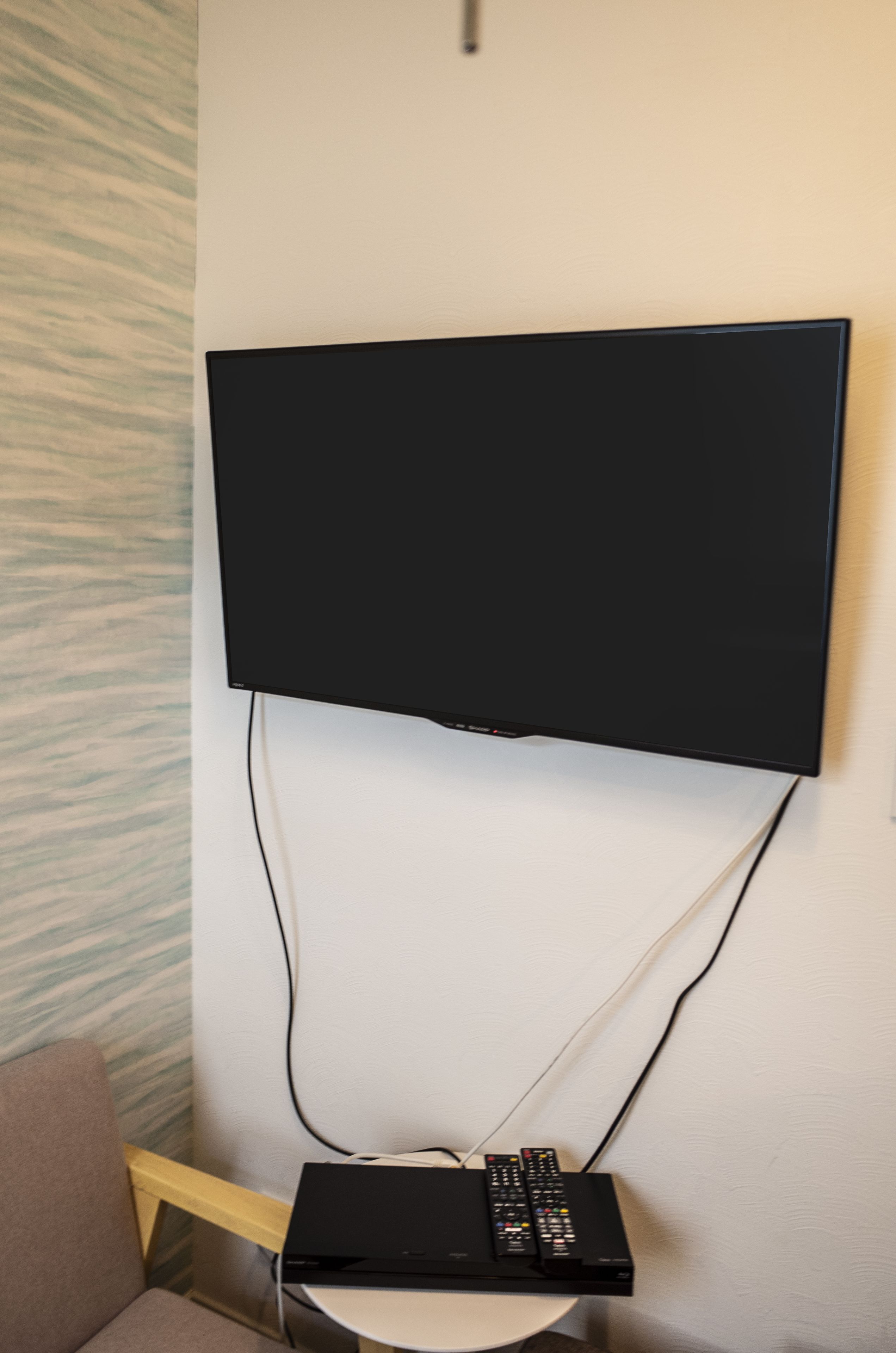 A flat-screen TV mounted on a wall with a cable box below it.