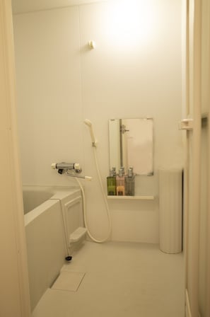 A small, white bathroom with a bathtub, a shower, a mirror, and a radiator. - LcHotel&Stay 2A (Tokyo)