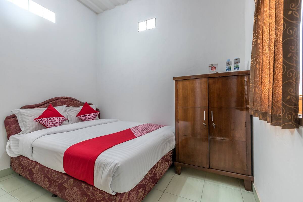 Une chambre à coucher avec un lit, une armoire en bois et une fenêtre.