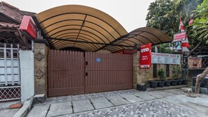 Une entrée fermée par un portail, avec un dallage menant à un bâtiment doté d’une toiture à structure incurvée.