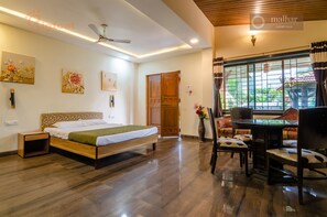 A bedroom with a bed, bedside table, and a window with curtains. - Malhar Villa (Murud)