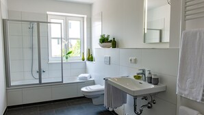 Une salle de bain moderne avec une douche à parois de verre, des toilettes et un lavabo surmonté d’un miroir.