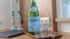 Une bouteille d’eau San Pellegrino et deux verres sur un plateau en bois.