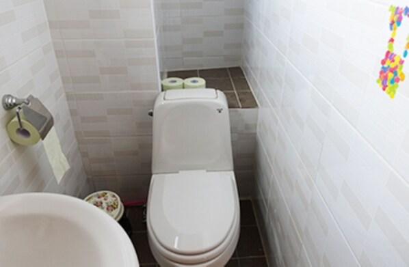 A small bathroom with a toilet, a bidet, and a toilet paper holder.
