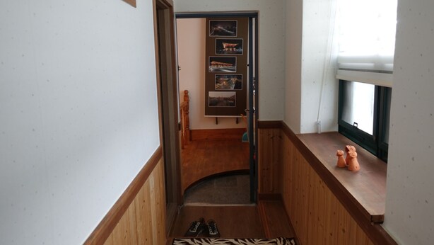 Un pasillo con piso de madera, alfombra estampada de cebra y una puerta que da a una habitación con ventana.