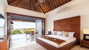 A spacious bedroom with a large bed, a wooden headboard, a balcony with outdoor seating, and a modern ceiling design. - Villa Lalang Temu (Jimbaran)
