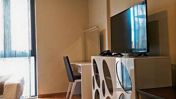 A compact living space with a bed, a desk, a television, and a refrigerator.